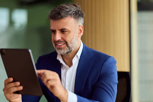 istock Confident Businessman In Blue Suit Using Tablet In Modern Office Setting For Professional Image 2249367851