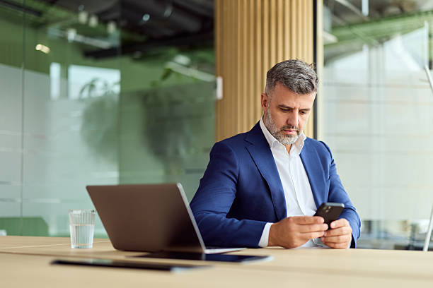istock Professional Office Worker In Blue Suit Focused On Phone At Modern Desk 2249367885