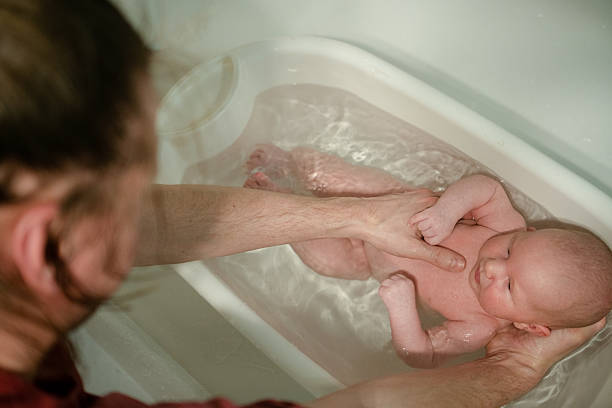 istock Tender moment of newborn bath with supportive parents hand 2249368978