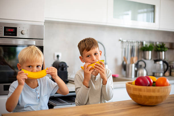 istock Boys eating healthy banana snack in modern kitchen 2249369743