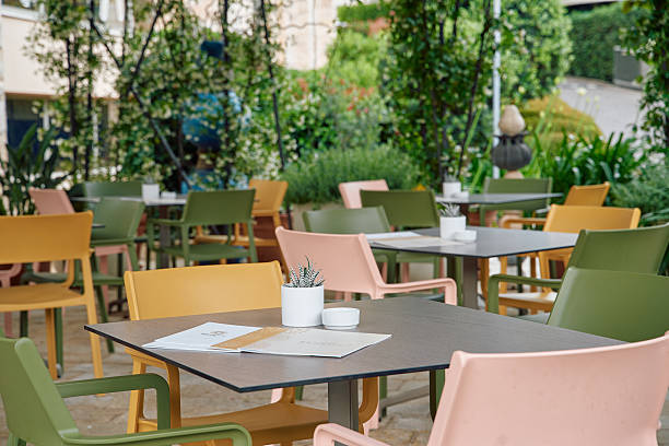 istock Charming Outdoor Dining Area Featuring Colorful Chairs and Tables Surrounded by Lush Greenery and Decorative Elements for a Cozy Ambiance 2249369799