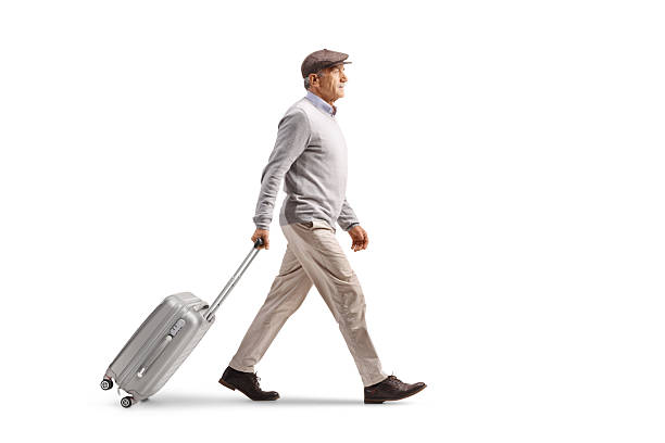 istock Full length profile shot of an elderly gentleman walking and pulling a suitcase 2249370022