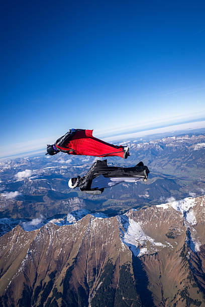 istock Wingsuit fliers fly face to face over snowcapped mountains 2249371584