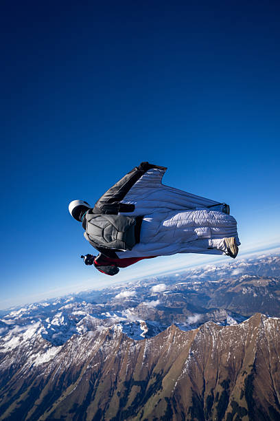 Wingsuit fliers fly face to face over snowcapped mountains, Swiss Alps