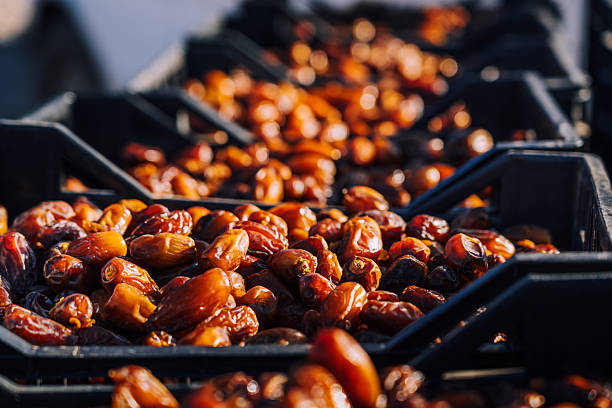 Ripe dates fill black crates in a bustling Moroccan market. Warm amber tones and a sense of everyday commerce evoke Erfoud’s traditional produce trade and vibrant local life.