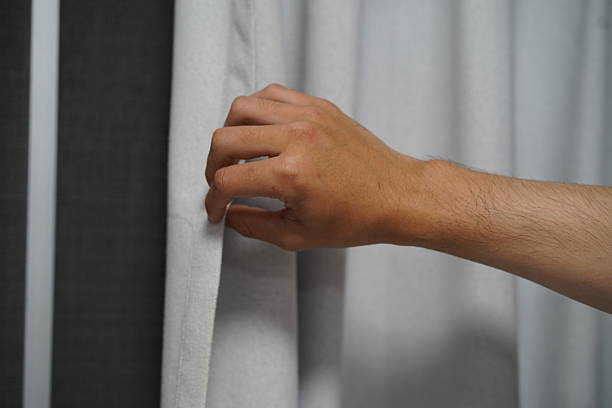 istock Hand Pulling Back Light Gray Curtain to Let in Natural Light in Modern Decor Living Space for Cozy and Inviting Atmosphere 2249373906
