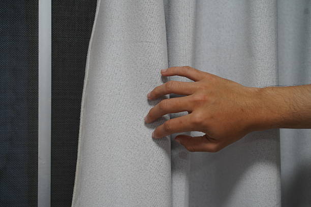 istock Hand Reaching for Soft White Textile Drapery in Modern Interior, Capturing Elegance and Textural Contrast in Fabric Design 2249374103