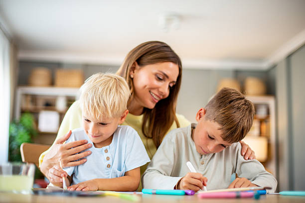 Loving mother assisting her two elementary age sons with schoolwork at home