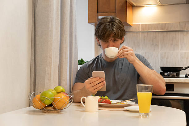 istock Drinking coffee and checking phone by young man. Healthy Breakfast. Home Kitchen Lifestyle 2249377568