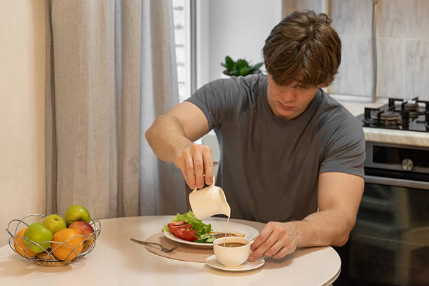 istock Pouring milk into coffee by young man. Healthy Breakfast. Home Kitchen Lifestyle 2249377592