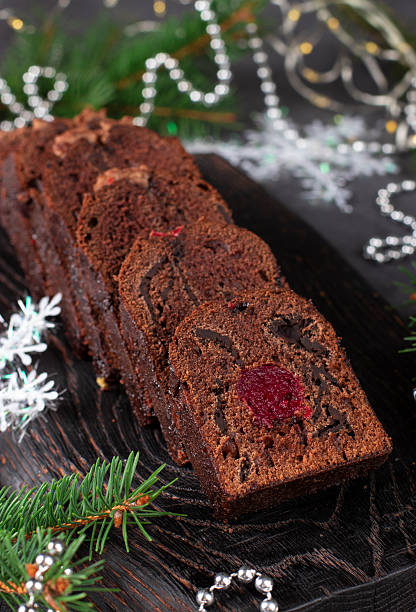 istock Sliced Christmas cupcake with cherries and chocolate covered with chocolate icing on wooden board 2249381081
