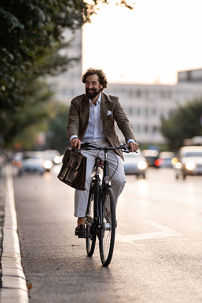 istock Businessman riding bicycle in city traffic during sunset commute 2249381423