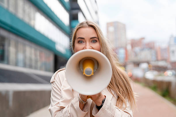 istock Woman holding megaphone promoting message in urban setting during cloudy day 2249388128