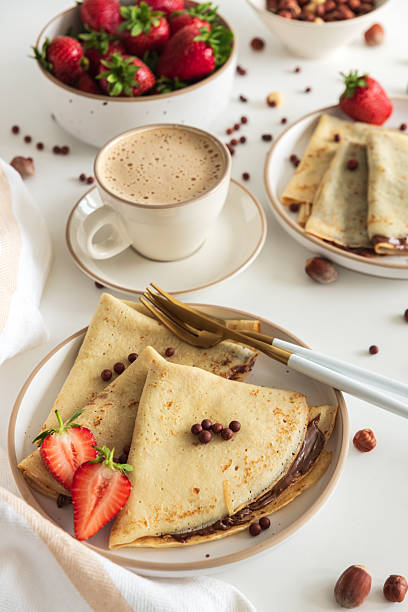 istock Crepes with chocolate hazelnut spread, strawberries and hazelnuts on a white wooden table. 2249396251