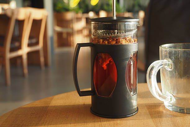 French Press With Freshly Brewed Tea on Wooden Table Under Warm Lighting