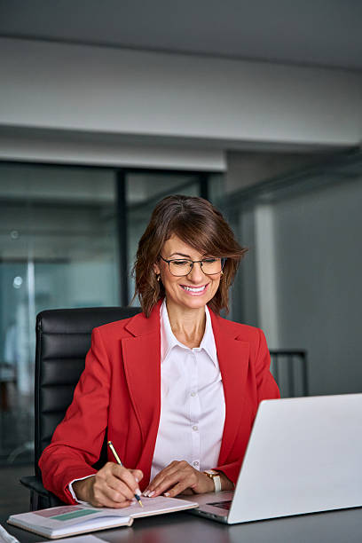 istock 40s middle-aged woman using laptop computer for business studying, having videocall online virtual webinar training meeting, writing notes. Focused mature businesswoman working in office. Vertical 2249399143