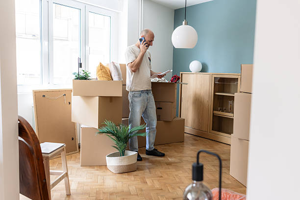 istock Man standing in a new home surrounded by moving boxes, talking on the phone 2249400476