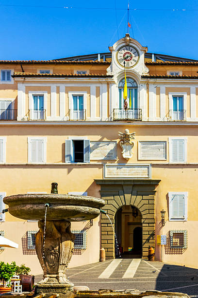 Castel Gandolfo, Italy - June 21, 2025: A view of the Pontifical Palace in Castel Gandolfo, featuring its elegant Baroque facade and the fountain in the main square under a clear blue sky.