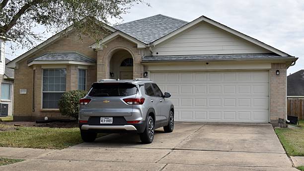 Houston, TX USA November 27, 2025 -  A striking portrait of a retro-style single-family brick home accented by a graceful tree, set in the heart of Houston, Texas. Also in its driveway is a grey-colored Chevy Trailblazer SUV.