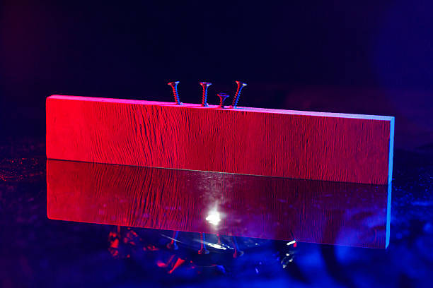 istock Screws screwed into a wooden beam in hard red light 2249408504