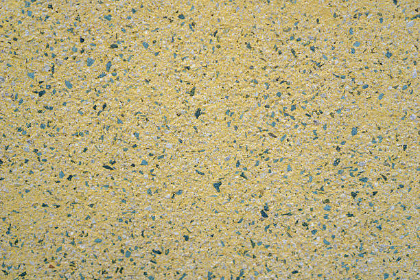 bright yellow exposed aggregate surface texture with speckled dark blue and green pebbles, detailed uniform construction background, concept of building material, architecture, modern flooring.