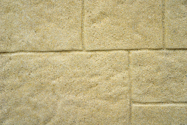 textured light sand-colored concrete paving stones with defined mortar lines, close-up uniform pattern, concept of construction, building material, landscaping.