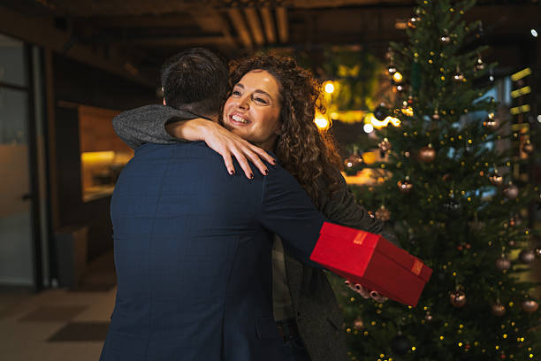 istock Office couple exchanging christmas gift and hugging during holiday party 2249417238