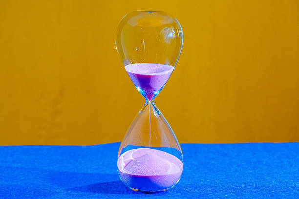 istock Hourglass in operation with pink sand falling and piling up at the base 2249418040