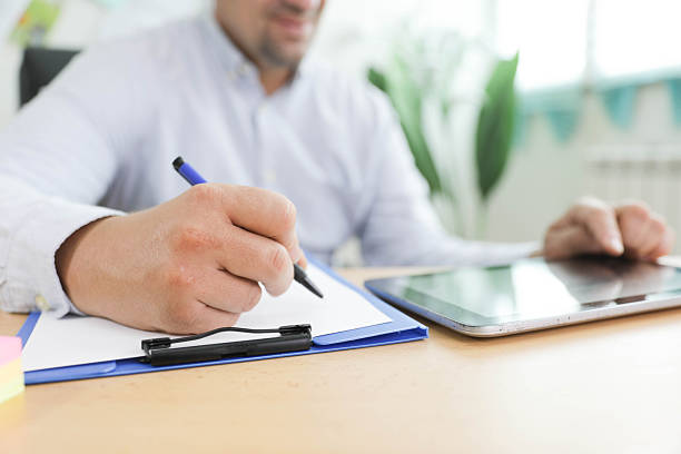 istock Senior Man Writing On Clipboard In Office 2249419788