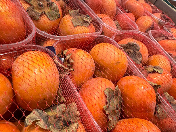 istock Fresh delicious persimmons in red netting at market display 2249419880