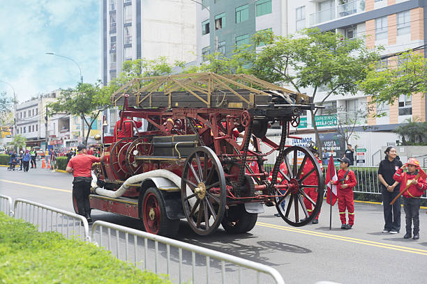 lima,peru, 11 30 2025.a classic red fire truck, likely from the early to mid-20th century, moving through a public space, possibly a street during a parade or public display.