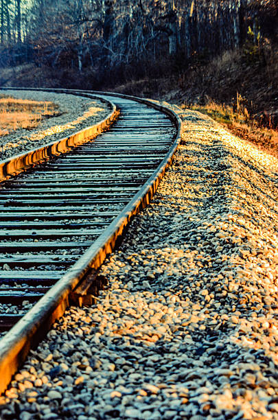 istock Empty curved railway tracks leading to the left during golden hour 2249422763
