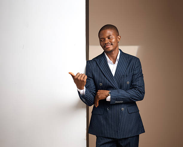 Studio portrait of man in pinstripe suit leaning on white panel and gesturing