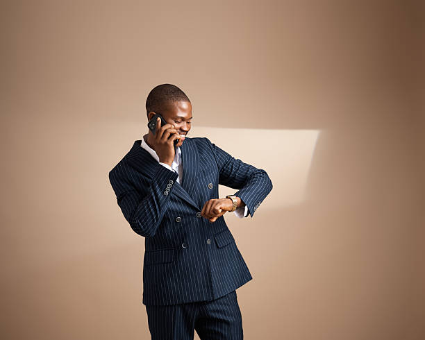 istock Man in pinstripe suit talking on phone and checking his watch in studio 2249427433