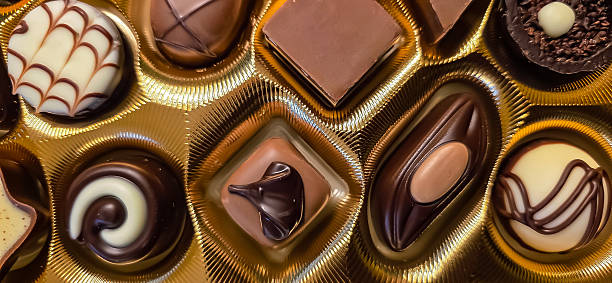 Assorted gourmet chocolates are displayed in an elegant golden box, showcasing rich textures and intricate designs, perfect for indulgent moments.