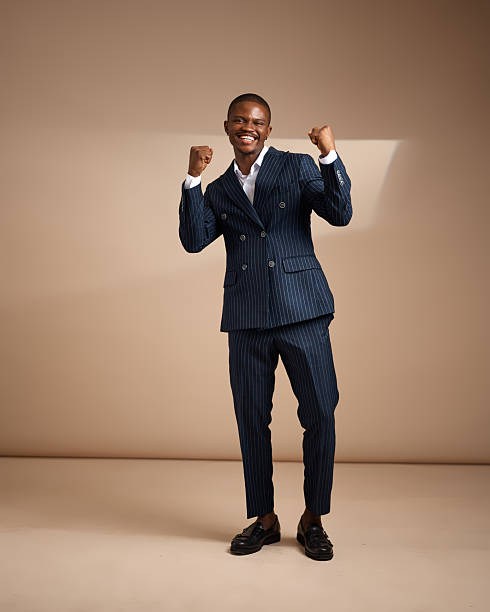 istock Man in pinstripe suit celebrating with raised fists in studio 2249428063