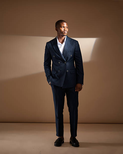 istock Man in pinstripe suit looking over shoulder in low-light studio scene 2249428146