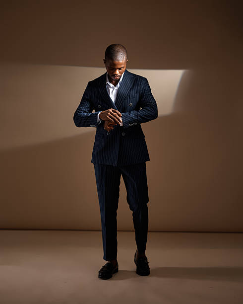 istock Man in pinstripe suit adjusting his sleeve in dramatic studio lighting 2249428177