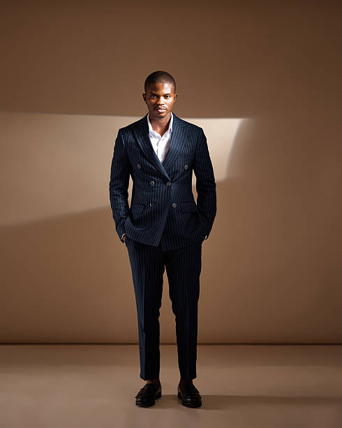 istock Man in pinstripe suit standing with hands in pockets in studio lighting 2249428182