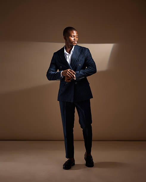 istock Man in pinstripe suit adjusting sleeve while standing in dramatic studio lighting 2249428195