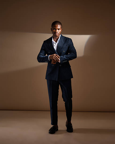 istock Man in pinstripe suit adjusting sleeve under dramatic studio lighting 2249428217