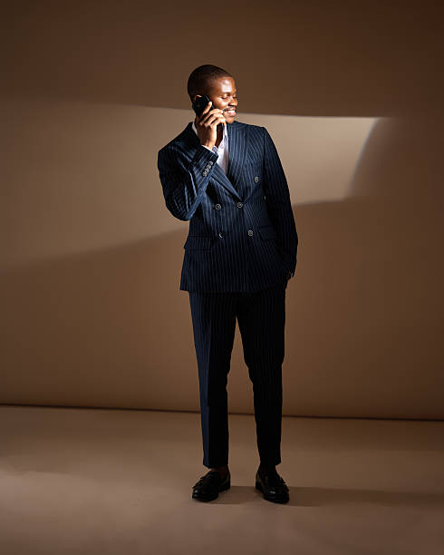 istock Man in pinstripe suit smiling while talking on phone in studio 2249428231
