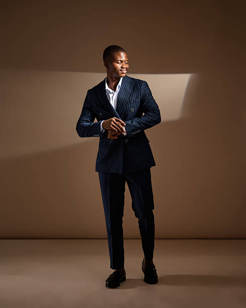 istock Man in pinstripe suit adjusting sleeve while looking to the side in studio 2249428263