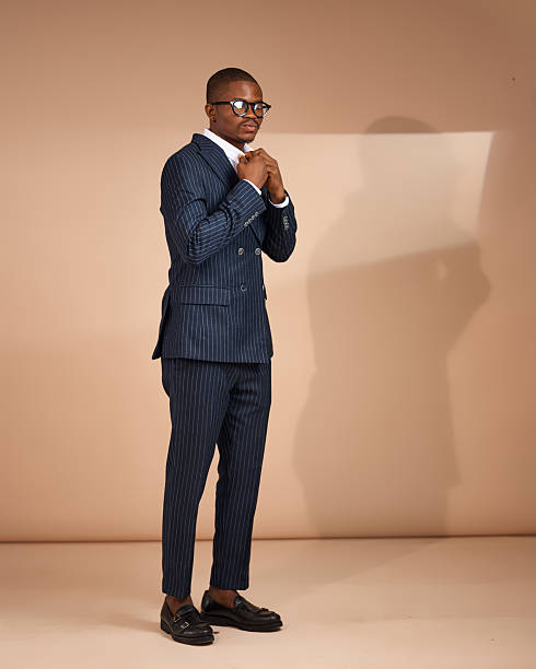 istock Man adjusting collar in pinstripe suit wearing glasses in studio 2249428654