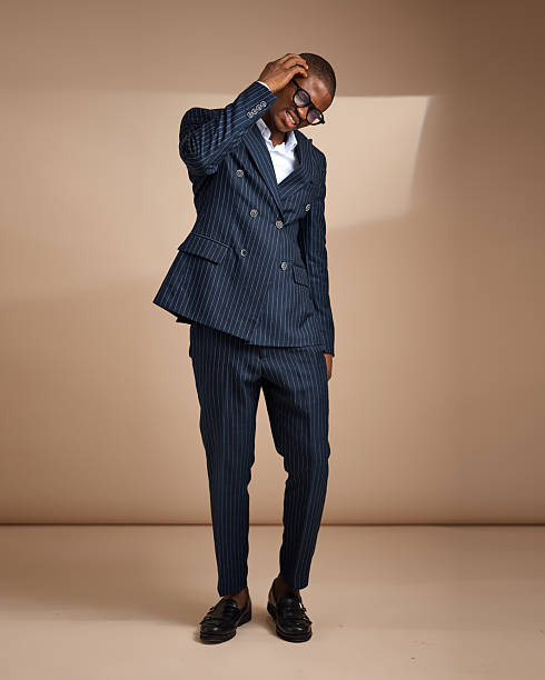 istock Man adjusting glasses while wearing pinstripe suit in studio 2249428808
