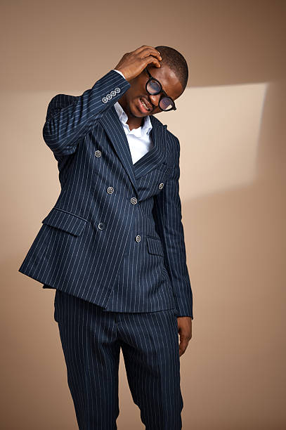 istock Man in pinstripe suit adjusting glasses in studio 2249428847