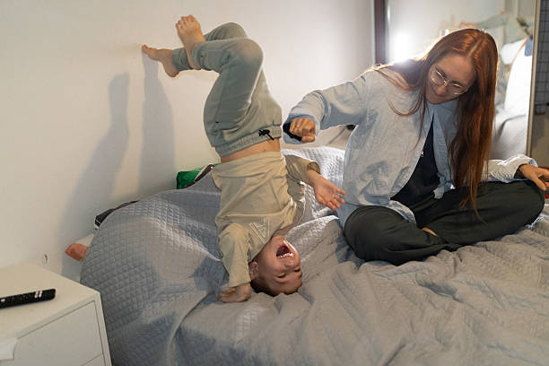 istock Child playing handstand on bed with parent laughing 2249429597