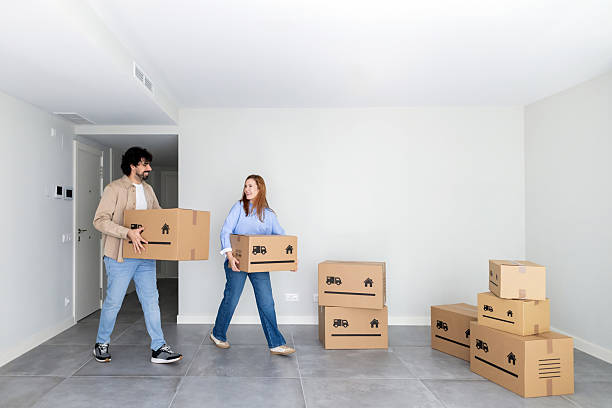 istock Couple moving into new house carrying carton boxes 2249433231