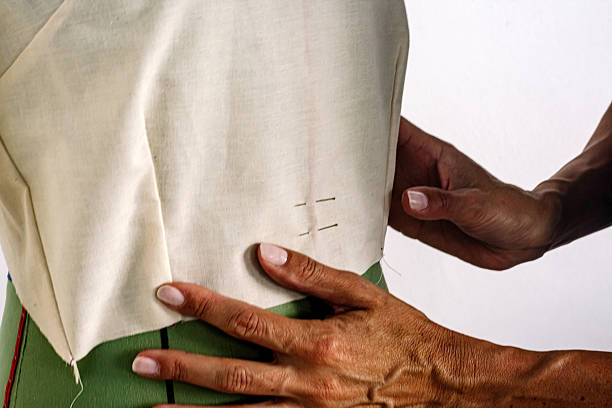 Close-up of clothier hands pinning sleeve to jacket armhole on male client