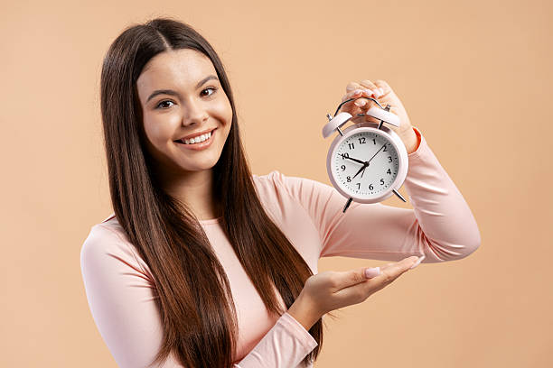 istock Young woman smiling while holding an alarm clock, managing time and punctuality concepts 2249437626